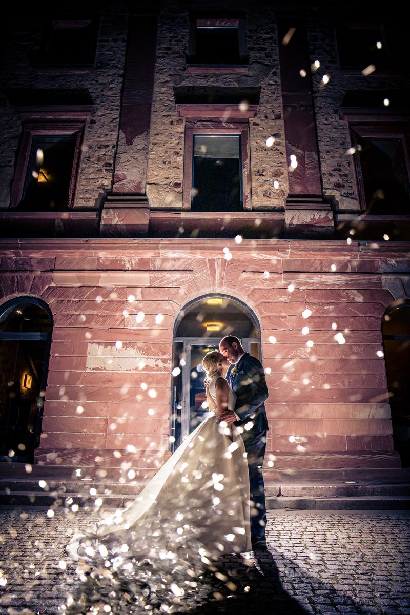Eine Braut und ein Bräutigam küssen sich vor dem Haupteingang im Jagdschloss Platte